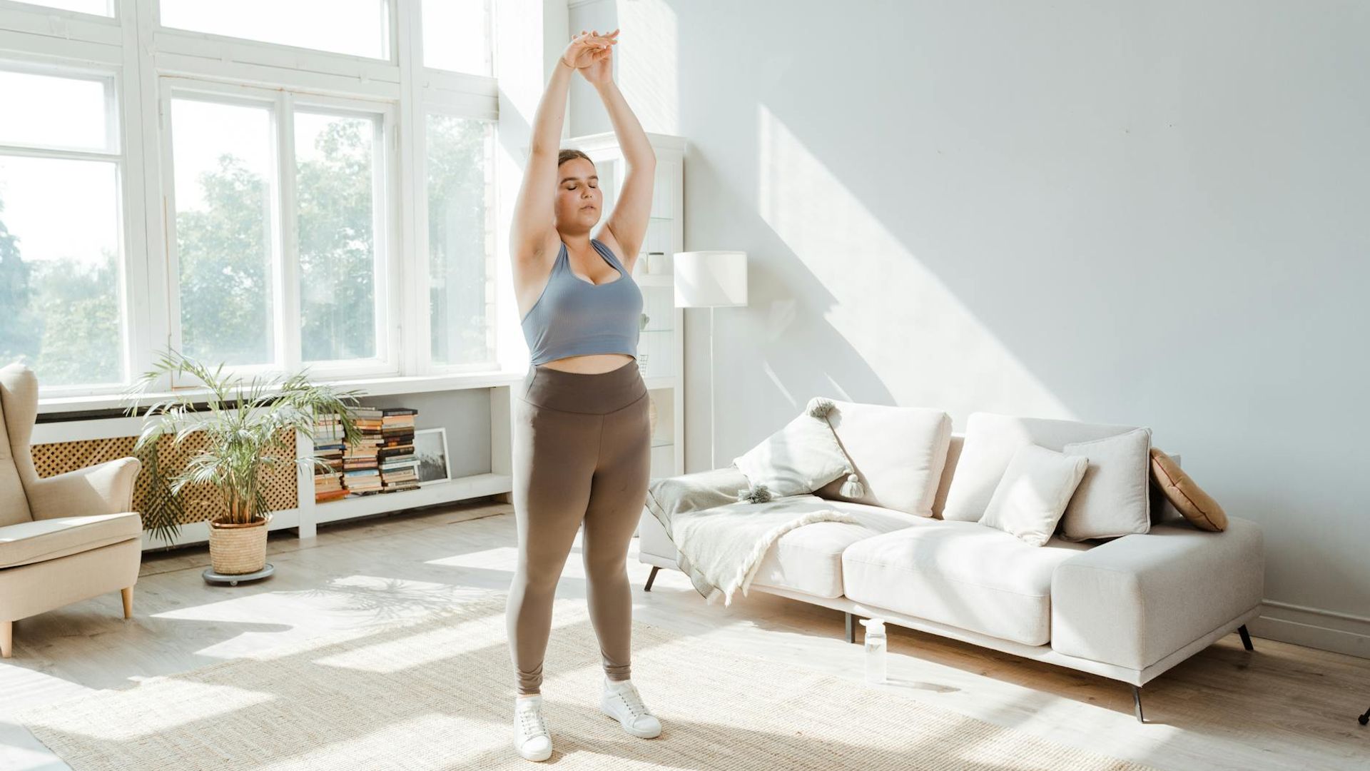 Woman performing gentle morning stretching in a sunlit room